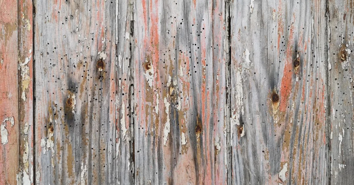 Primer plano de tablones de madera envejecidos con pintura descascarada y superficie texturizada.