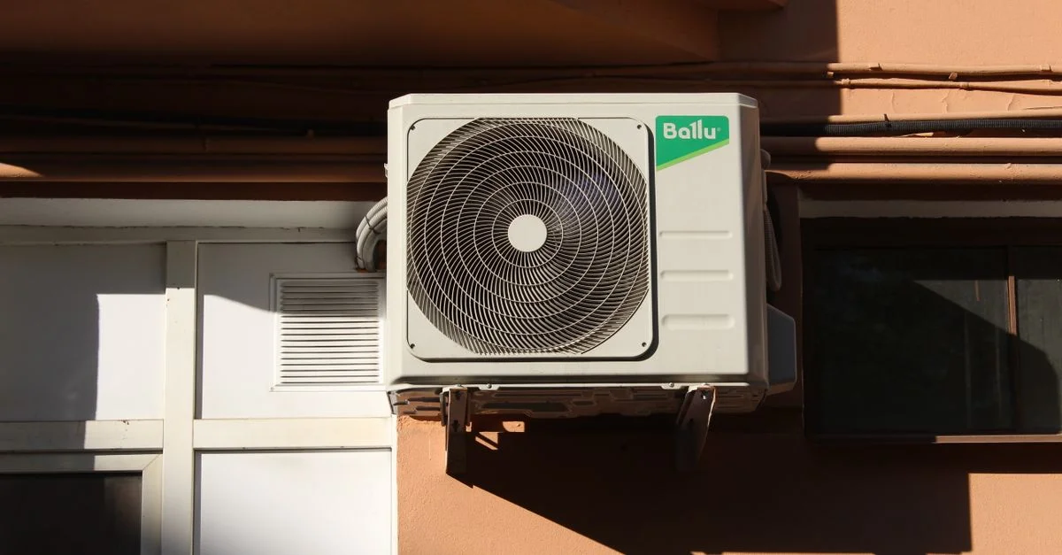 Una unidad condensadora de aire acondicionado Ballu montada en el exterior de un edificio, mostrando la moderna tecnología HVAC.