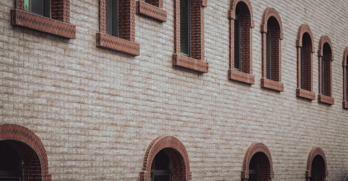 Vista exterior de un edificio de ladrillo con ventanas arqueadas simétricas de estilo clásico.