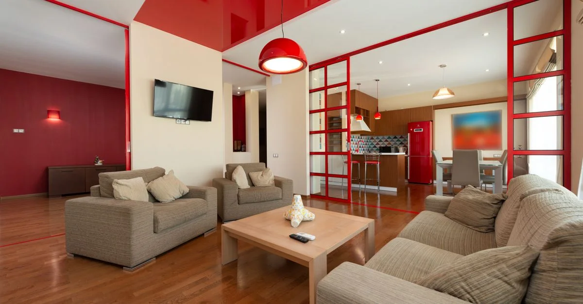 Amplio salón moderno con acentos rojos, distribución abierta y muebles contemporáneos.
