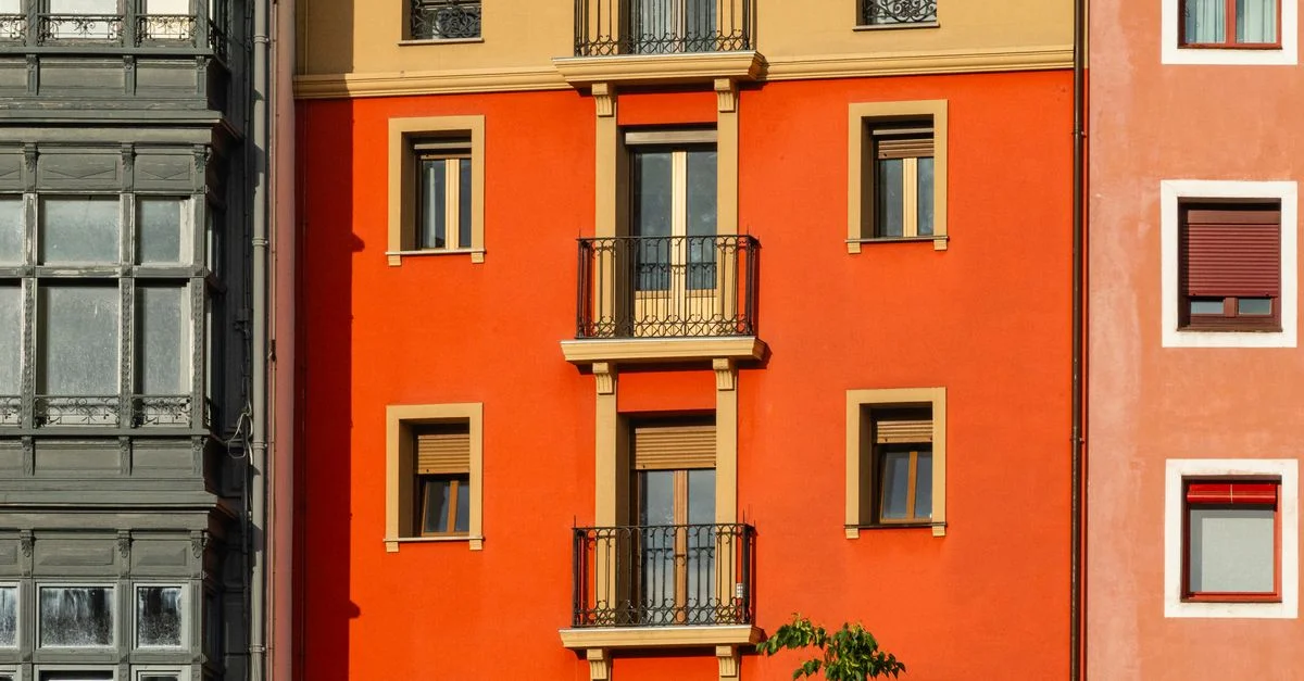 Fachada de un edificio de apartamentos de colores vivos, con elementos arquitectónicos y ventanas que contrastan entre sí.