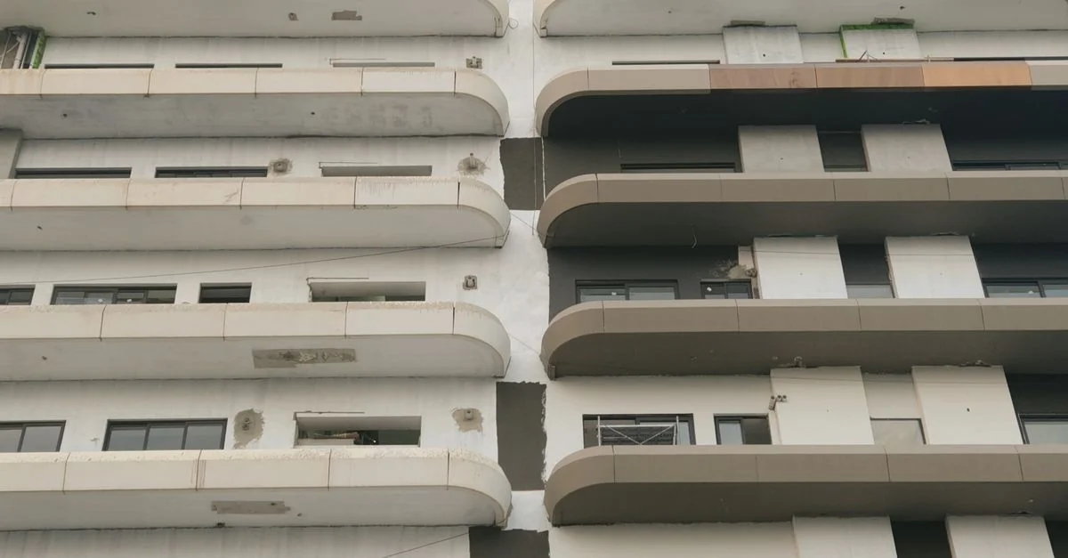 Primer plano de la fachada de un edificio moderno que muestra balcones y patrones geométricos, resaltando los detalles arquitectónicos.