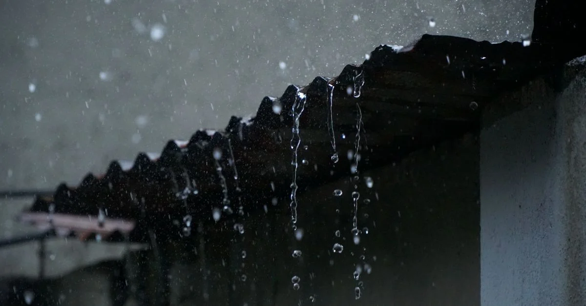 Primer plano del agua de lluvia cayendo de un tejado de chapa en Long Khánh, Vietnam.